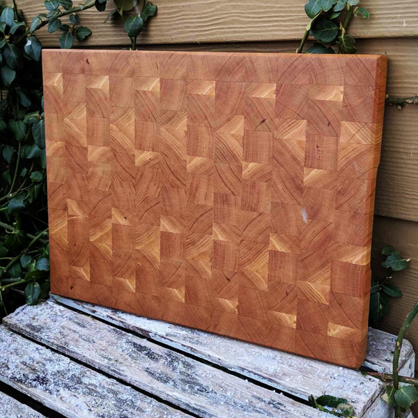 Top-down view of cherry cutting board highlighting wood grain and bevel