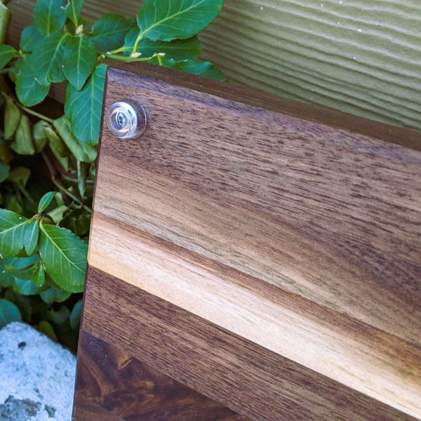 Black walnut wood edge grain cutting board with beveled edge.