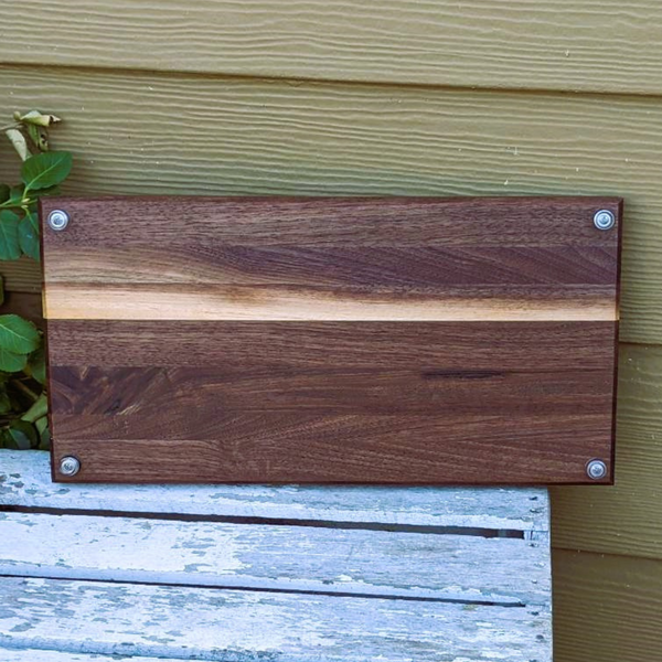 Black walnut wood edge grain cutting board with beveled edge.
