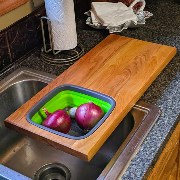Cherry wood wooden cutting board with removable collapsivle colander strainer and clear rubber grip feet. Cherry Wood Edge Grain Cutting Board with Colander and Clear Rubber Grip Feet