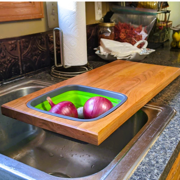 Cherry wood wooden cutting board with removable collapsivle colander strainer and clear rubber grip feet. Cherry Wood Edge Grain Cutting Board with Colander and Clear Rubber Grip Feet