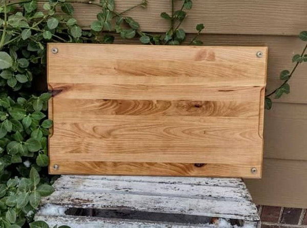 Cherry Wood edge grain cutting board with hand grooves and clear rubber grip feet.