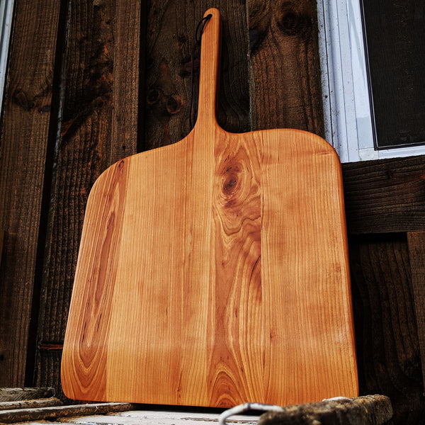 Close-up of cherry pizza peel face showcasing natural wood grain and satin finish.