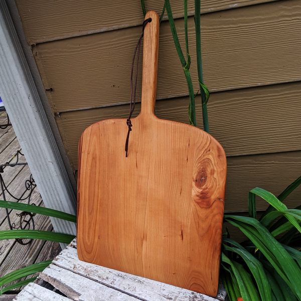 Flat lay of cherry pizza peel showing full surface and handle from above
