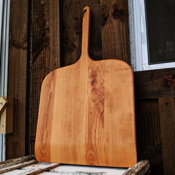 Cherry pizza peel shown with round serving tray for scale comparison