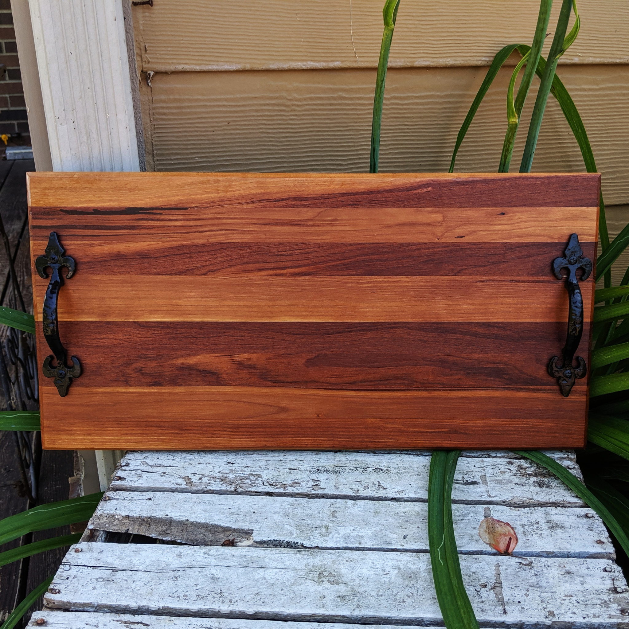 Front view of handcrafted spalted cherry wood charcuterie board with cast iron handles and rubber feet