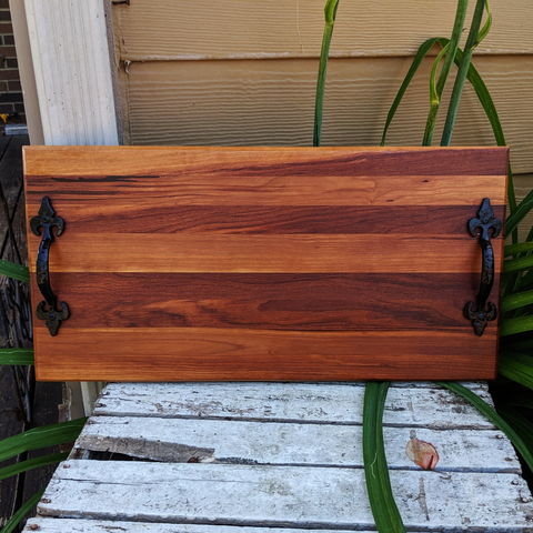 Front view of handcrafted spalted cherry wood charcuterie board with cast iron handles and rubber feet