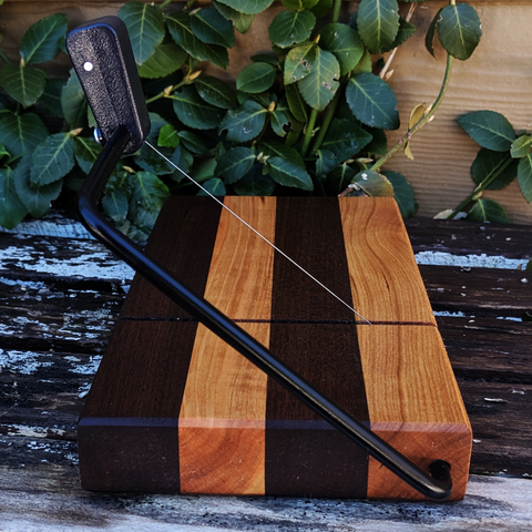 Front view of black walnut and cherry cheese slicer board with built-in groove