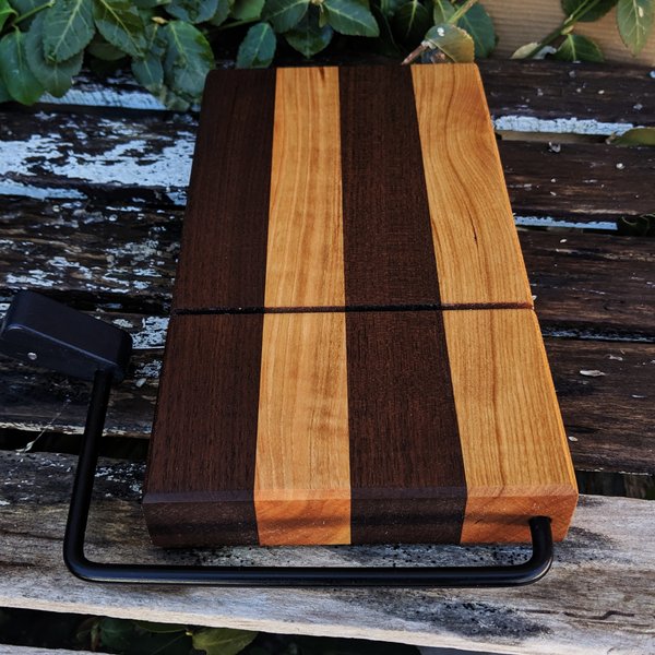 Cheese slicer board made of black walnut and cherry placed on kitchen counter