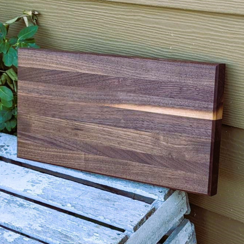 Black walnut wood edge grain cutting board with beveled edge.