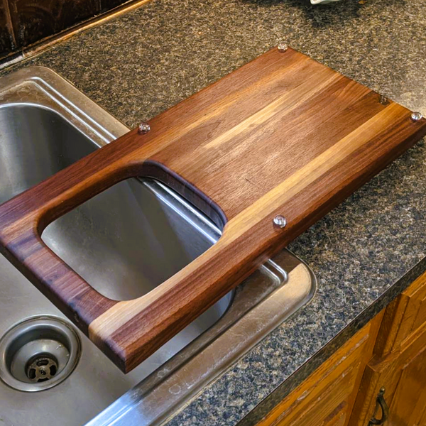 Over the sink Black Walnut edge grain cutting board with removable colander / strainer and clear rubber grip feet.