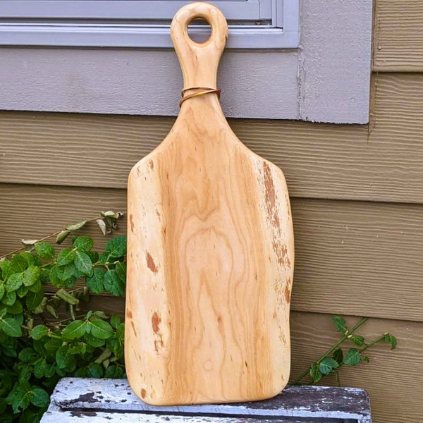 Cherry wood wooden charcuterie paddle serving board with handle and leather strap.