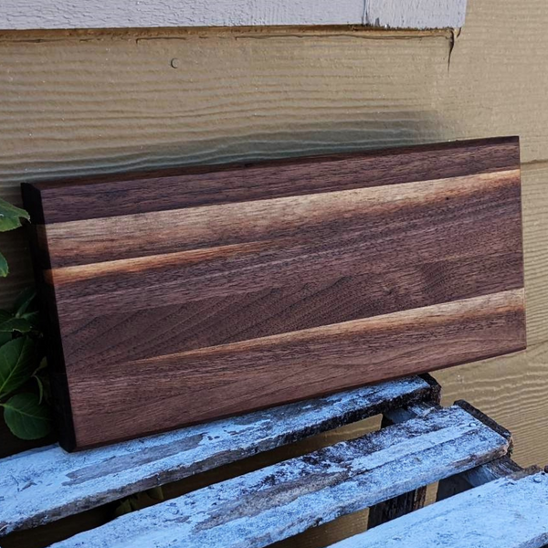 Black walnut edge grain cutting board with beveled edge.