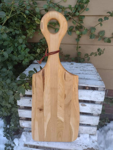 Handmade Cherry Wood charcuterie board paddle with handle and leather strap for easy storage options.