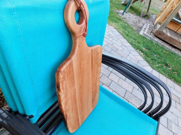 Cherry Wood charcuterie board with handle and leather strap for easy handling and storage options.