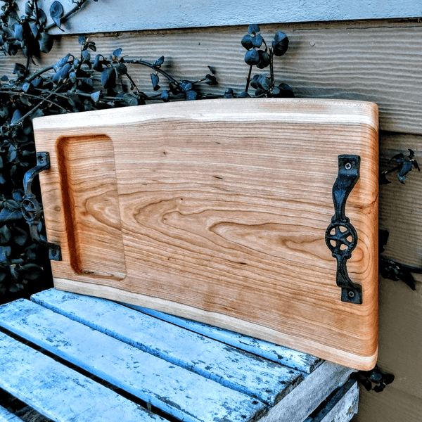 Cherry Wood charcuterie board tray with heavy duty cast iron handles and clear rubber grip feet.