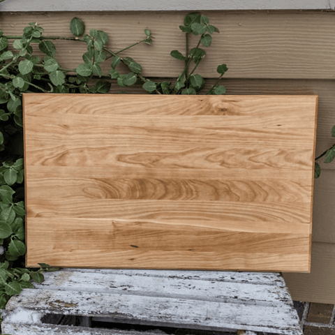 Cherry Wood edge grain cutting board with hand grooves and clear rubber grip feet.