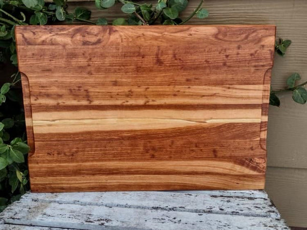 Cherry Wood edge grain cutting board with hand grooves on bottom sides and beveled edge.