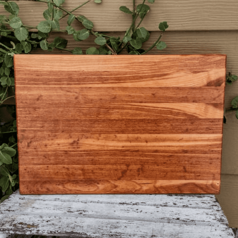 Cherry Wood edge grain cutting board with hand grooves on bottom sides and beveled edge.