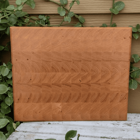 End grain Chery Wood cutting board with beveled edge and clear rubber grip feet.