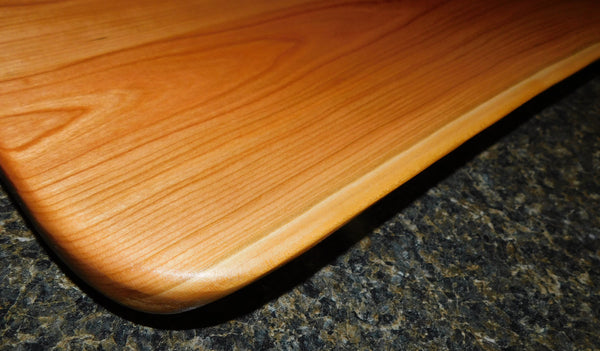 Cherry Wood charcuterie board with knots sealed using translucent epoxy to create a unique finish. Entire board is finished in a food grade oil & beeswax mixture to give it a beautiful sheen, making it usable on both very unique sides. Rubber feet are attached to provide stability and avoid surface marring associated with dark rubber.  Size: 20 in. x 13.75 in. x 1 in. (approximately) Springhill Millworks