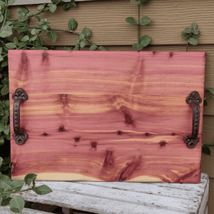 Red Cedar charcuterie board with heavy duty cast iron handles and clear rubber grip feet.